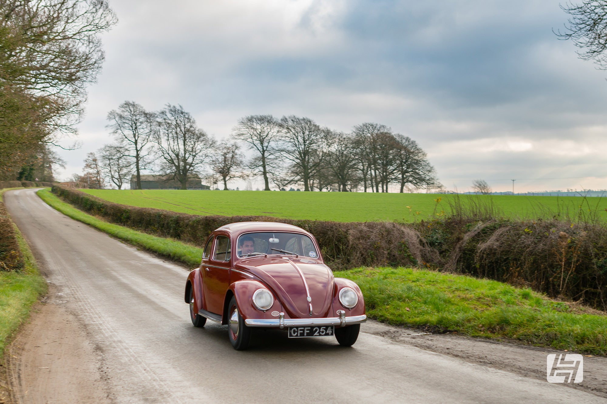 Garnet Red VW Beetle driving in the countryside 