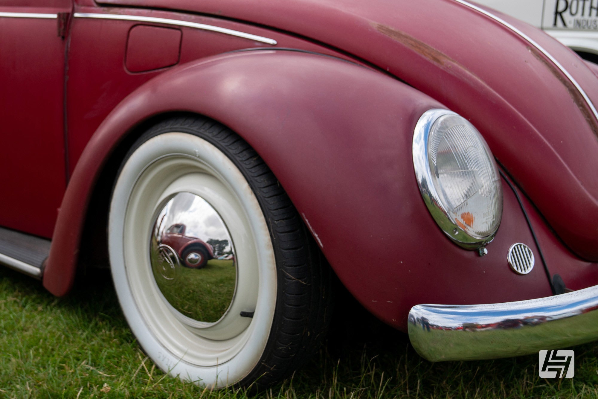 Pre 1967 front wings fitted to matt red VW Beetle with white wall tyres and chrome hubcaps