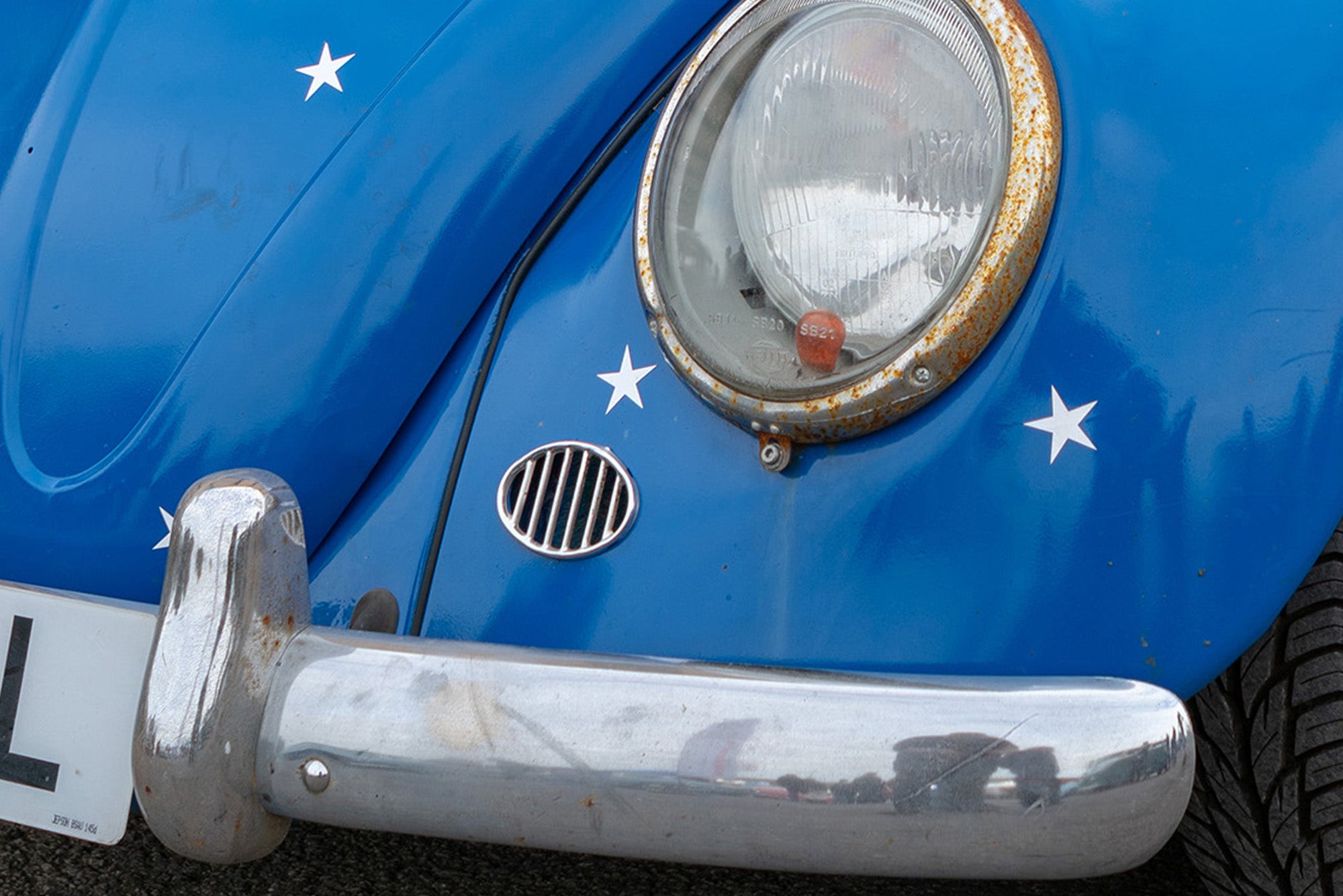 Blue VW Beetle with rusty headlamp rim, blade bumpers and european style over-rider fitted