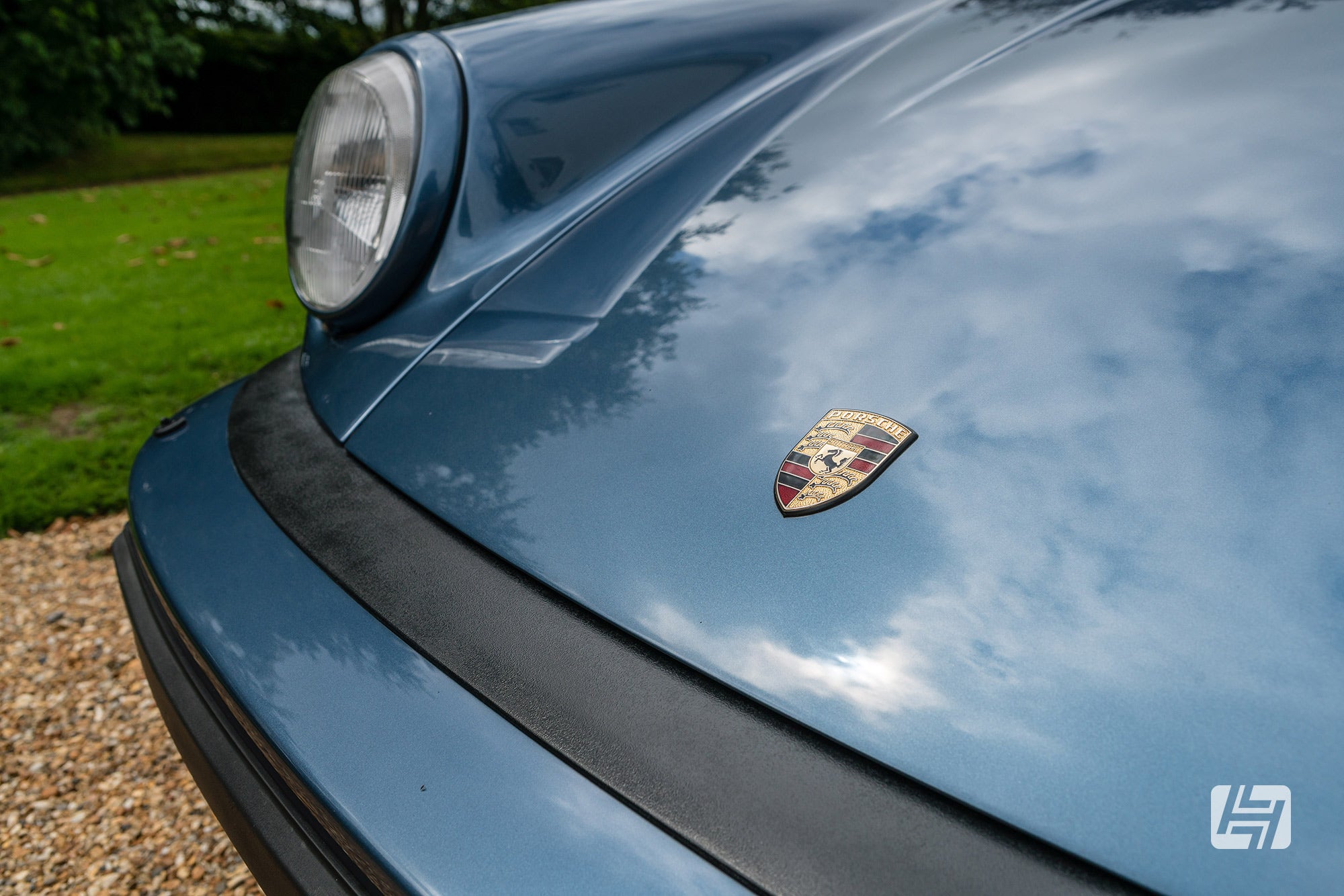 Close up of Porsche badge and bumper to bonnet seal on blue Porsche 911 Gbody car