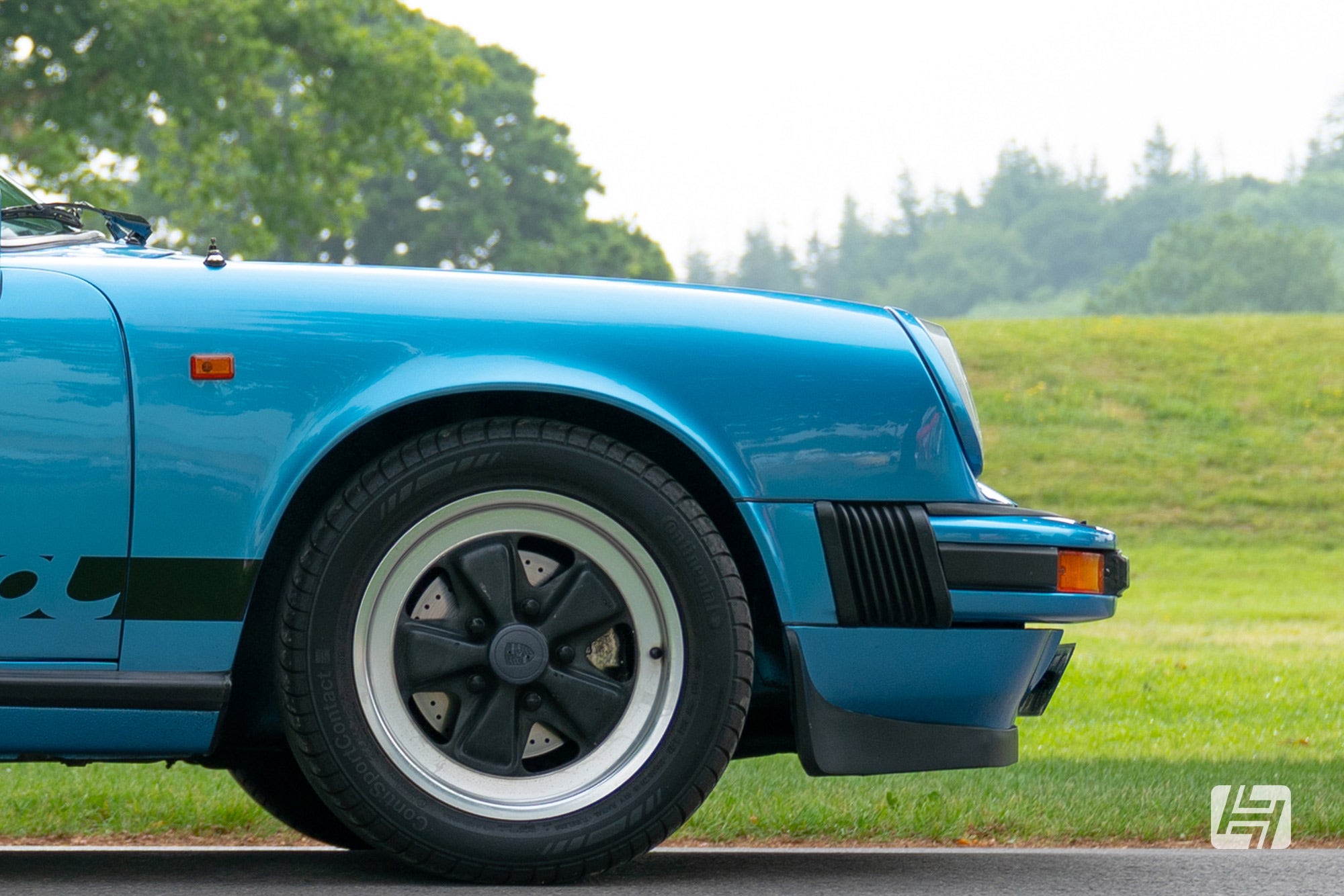 Front end of blue Porsche 911 G body with black centred Fuchs wheels and amber indicators